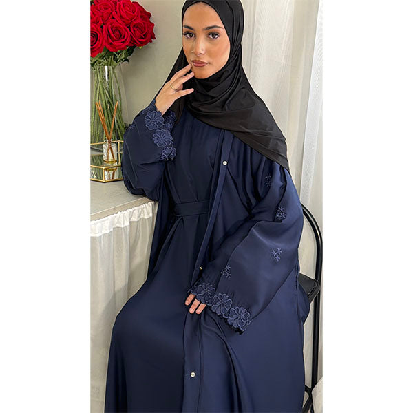 A Women Wearing A Navy Floral Embroidered Elegant Detailed Sleeve Open Button A-Line Cut  Abaya In Shiny Satin Type Fabric with Side Pockets in Size 52 fits a Size 6-16