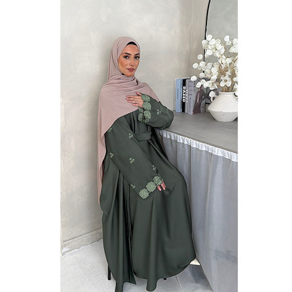 A Women Wearing A Sage Floral Embroidered Elegant Detailed Sleeve Open Button A-Line Cut  Abaya In Shiny Satin Type Fabric with Side Pockets in Size 52 fits a Size 6-16