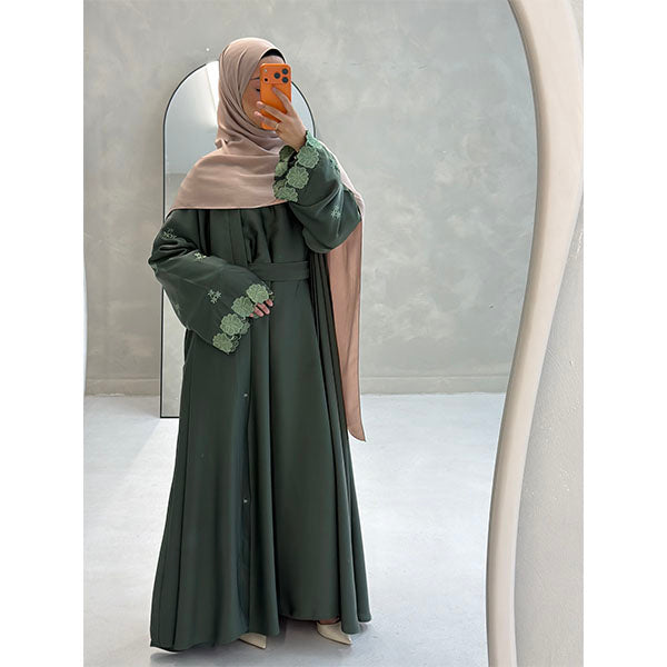 A Women Wearing A Sage Floral Embroidered Elegant Detailed Sleeve Open Button A-Line Cut  Abaya In Shiny Satin Type Fabric with Side Pockets in Size 52 fits a Size 6-16